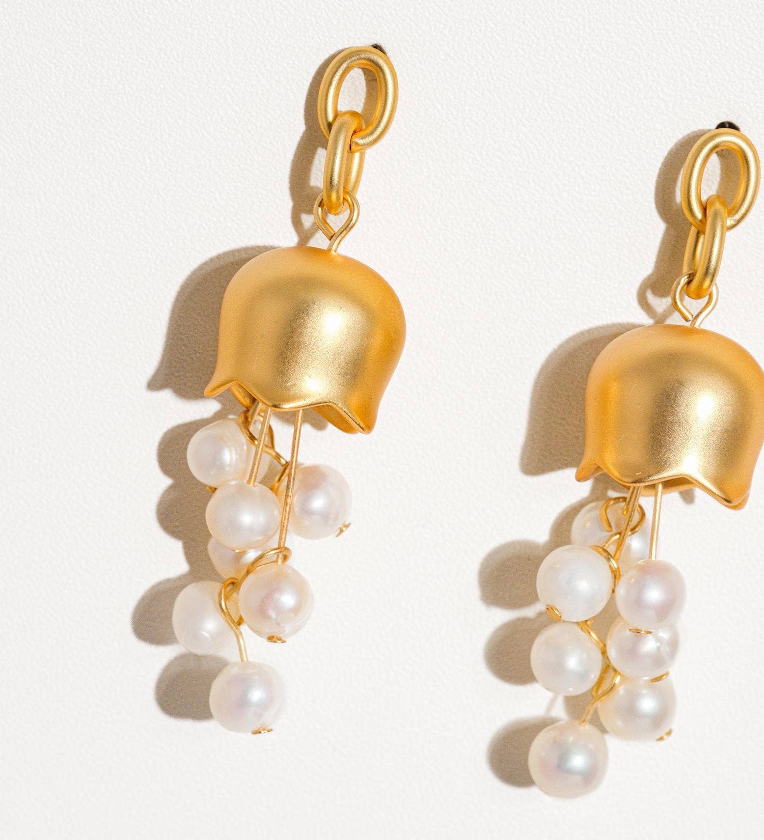 Sculptural bellflower earrings crafted from a brass base with 18K matte gold plating, featuring luminous freshwater pearls for a soft, elegant look. Hypoallergenic, water- and tarnish-resistant—perfect for adding blooming floral charm and timeless sophistication to any outfit.