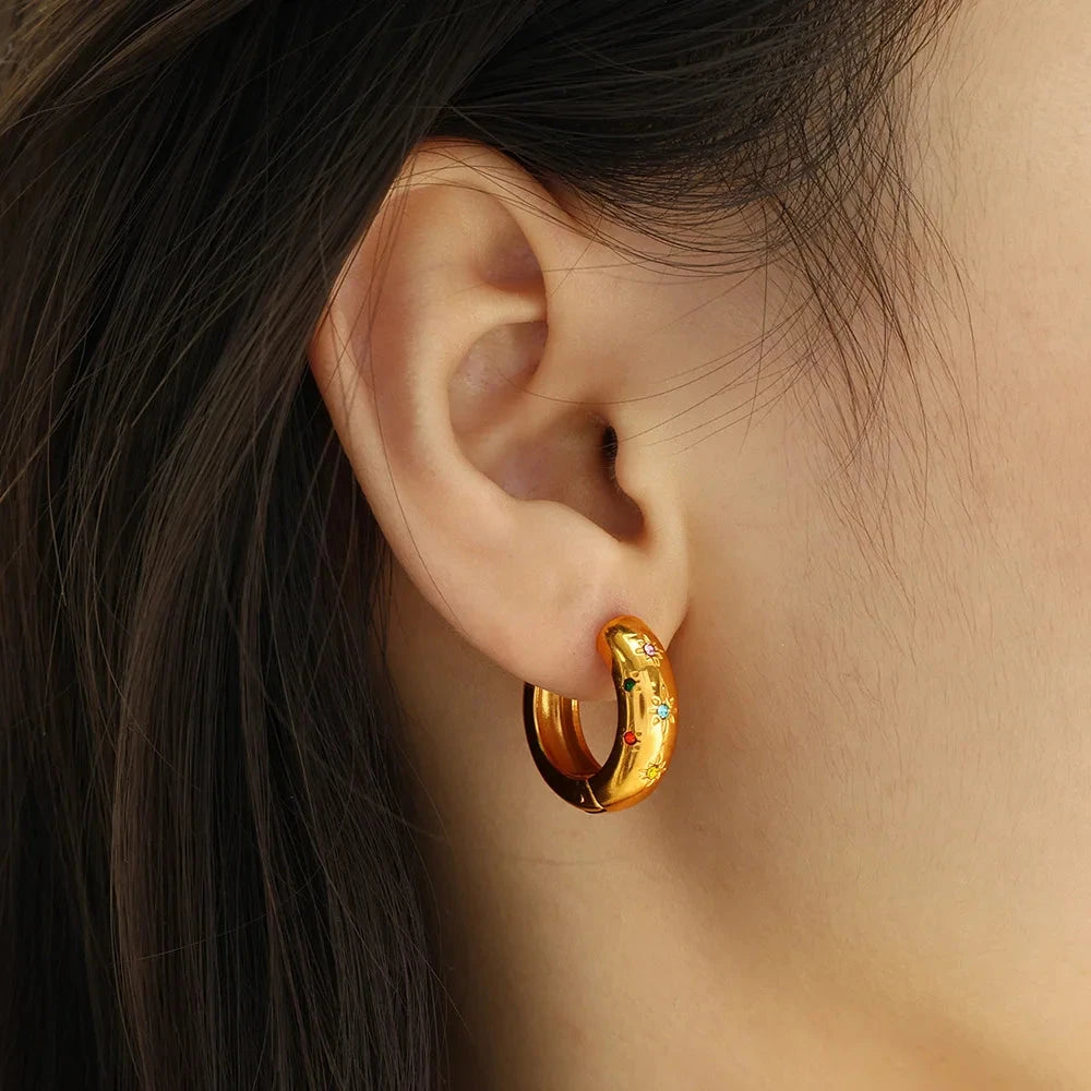 Chunky huggie hoop earrings crafted from 18K gold-plated stainless steel, featuring bold multi-coloured zircon inlay for vibrant sparkle. Hypoallergenic, water- and tarnish-resistant—perfect for adding a radiant pop of colour and trend-forward style to any look.