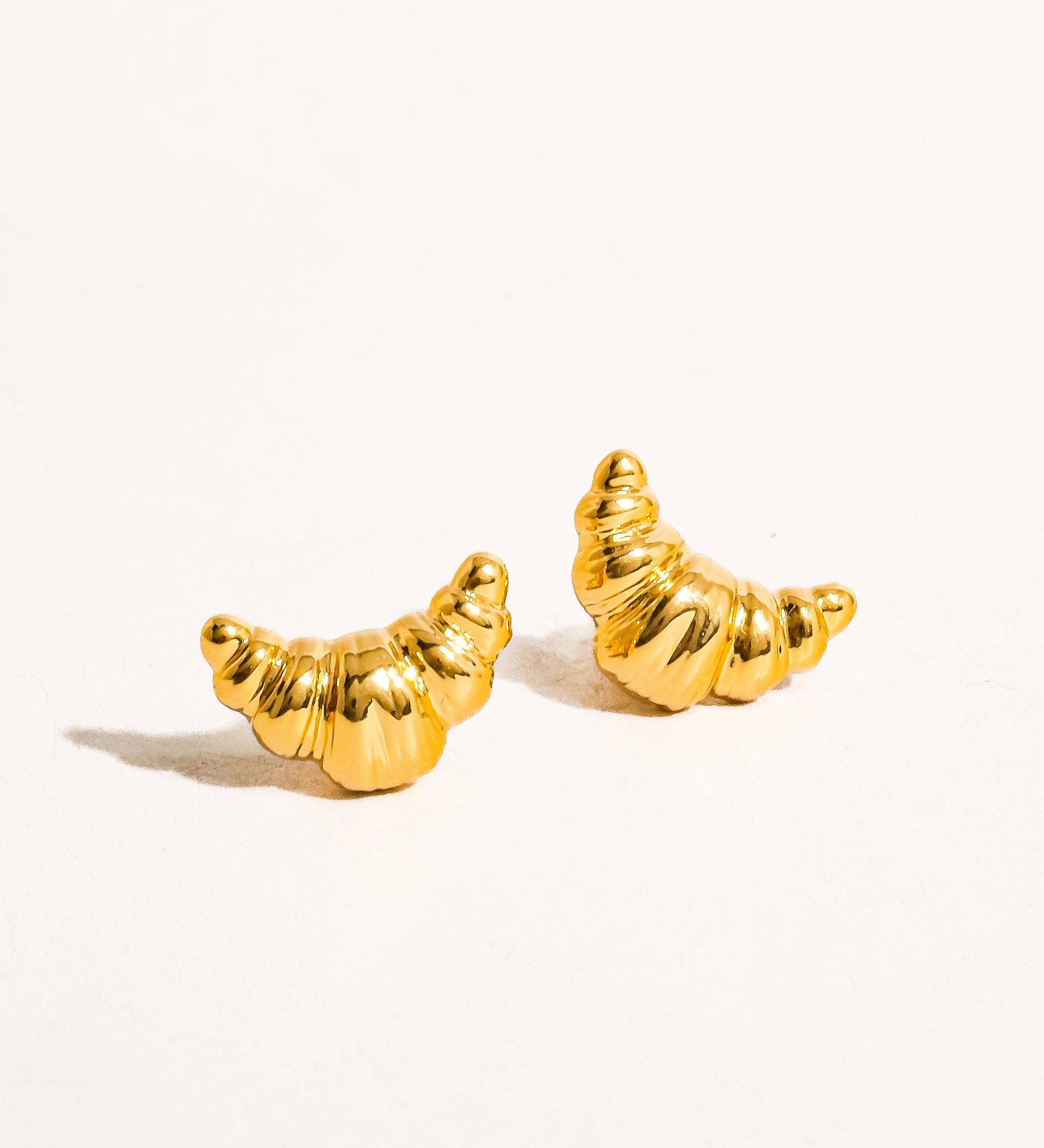 Petite sculptural stud earrings crafted from a brass base with premium 18K gold or silver plating, featuring a modern croissant-inspired design. Minimalist and Parisian-chic—perfect for adding a stylish twist to any everyday look. Hypoallergenic, water- and tarnish-resistant.