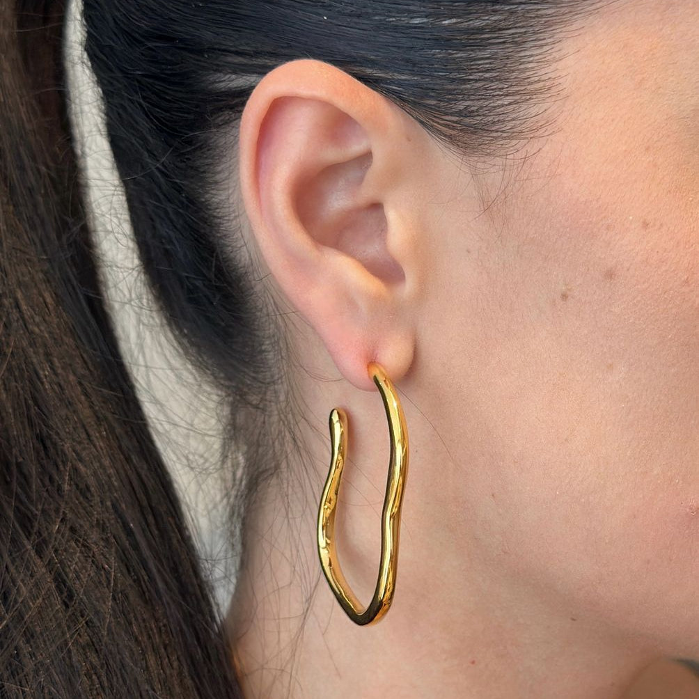 Curved hoop earrings crafted from 18K gold-plated stainless steel, featuring a unique sculptural silhouette that blends bold style with refined elegance. Hypoallergenic, water- and tarnish-resistant—perfect for making a statement from day to night.