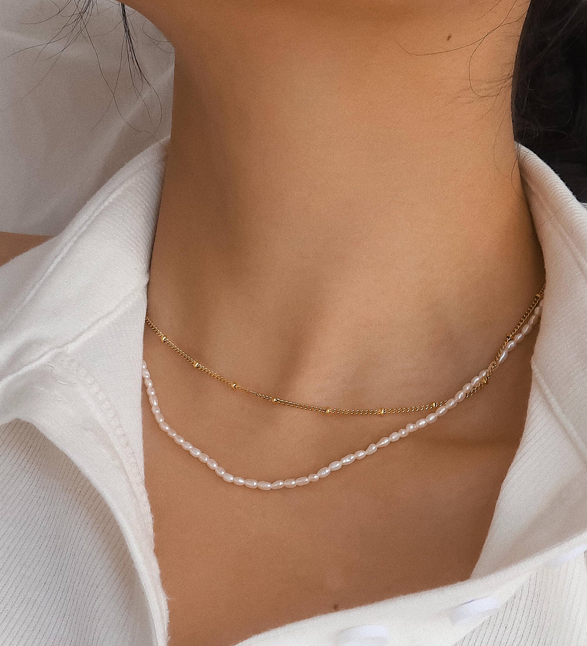 Dual-layered necklace crafted from 18K gold-plated stainless steel, featuring delicate freshwater pearl detailing. Measures approx. 15 inches with a 2-inch extender. Hypoallergenic, water- and tarnish-resistant—perfect for blending modern layering with timeless elegance.