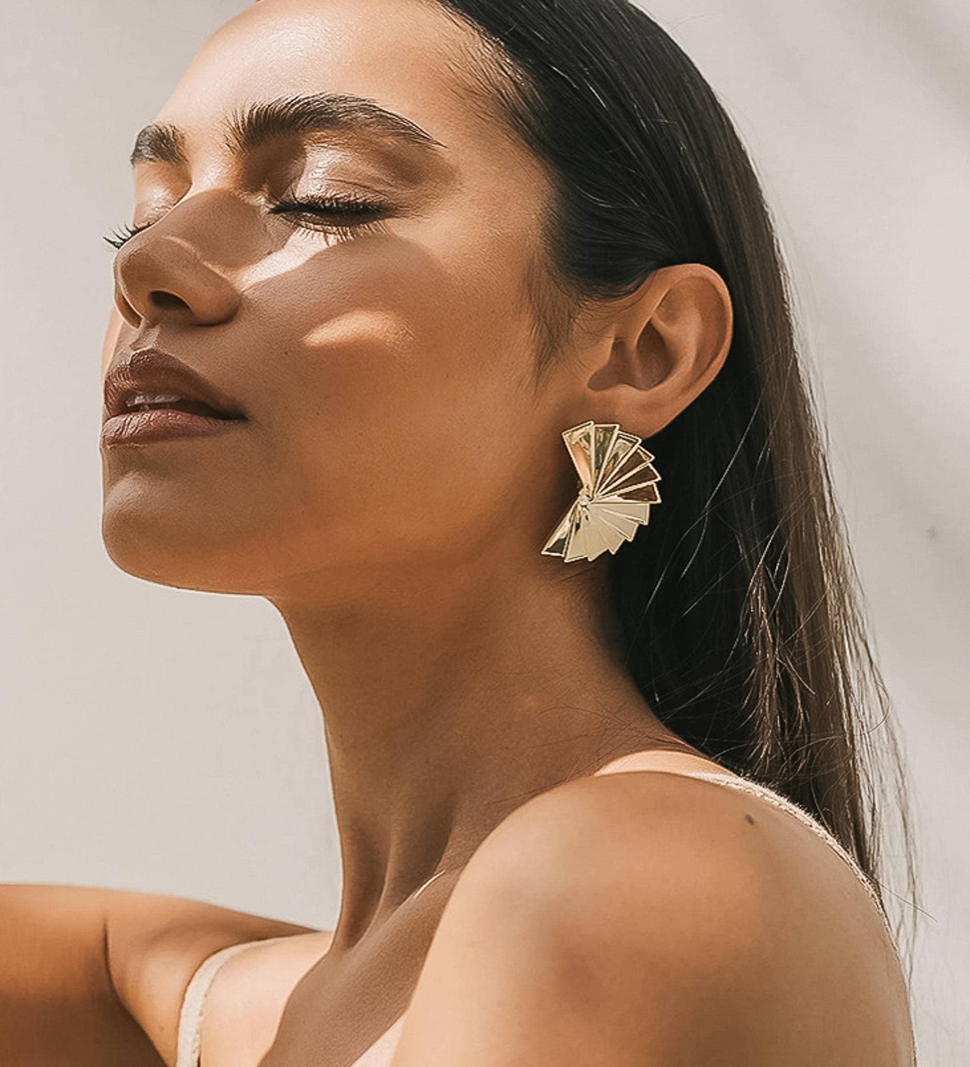 Sculptural earrings with a folded fan silhouette, featuring elegant curves and a high-shine gold finish. Made from 18K gold-plated stainless steel, measuring 1.56 x 1.2 inches. Hypoallergenic, water- and tarnish-resistant—an artful statement for day or night wear.