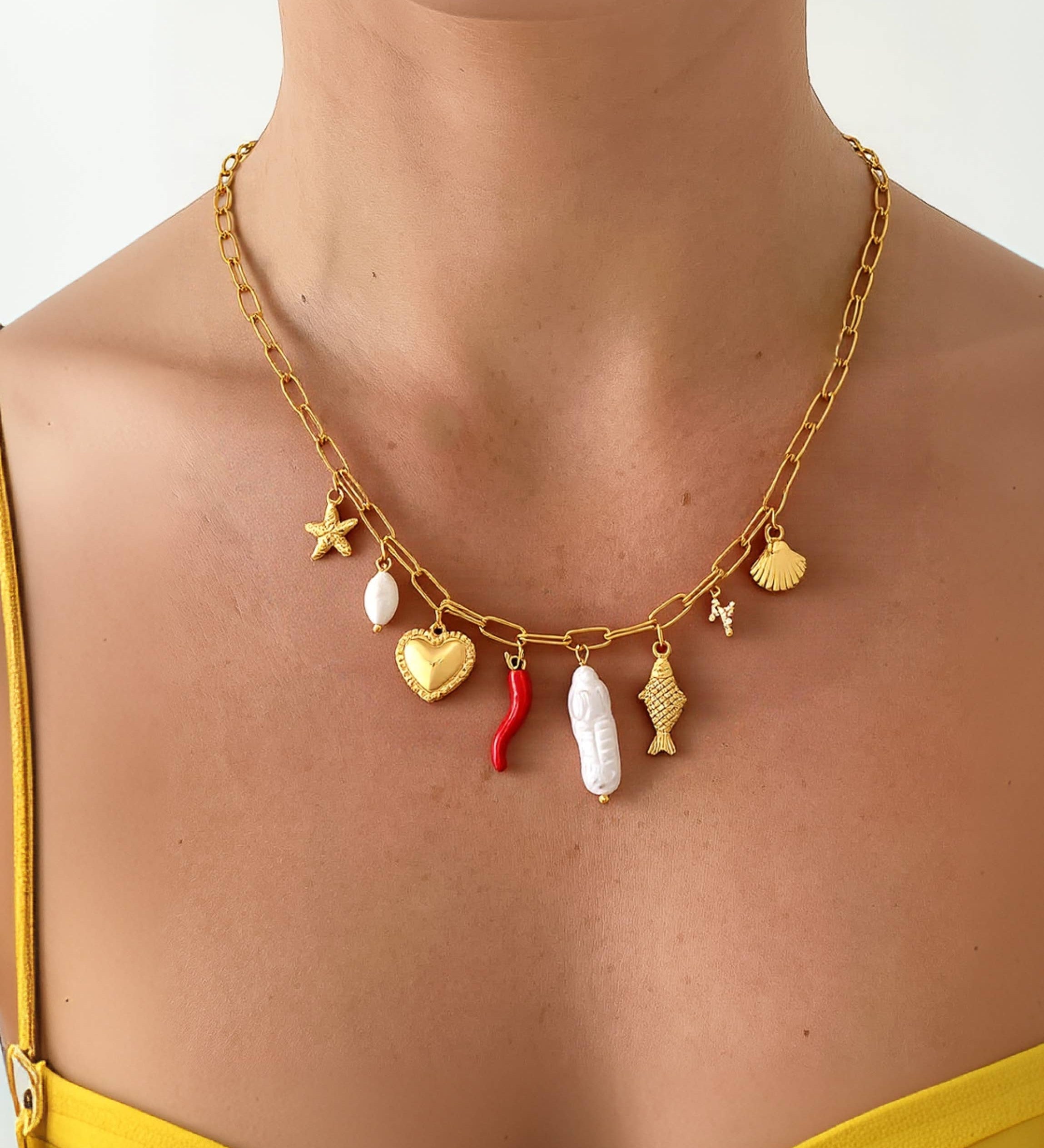 Delicate gold necklace featuring playful ocean-inspired charms—a fish and a pearl—on an 18K gold-plated stainless steel chain. Pendant measures 0.5 to 1.1 inches; chain is 17.7 inches with a 2-inch extender. Hypoallergenic, water- and tarnish-resistant—perfect worn solo or layered for a whimsical touch.