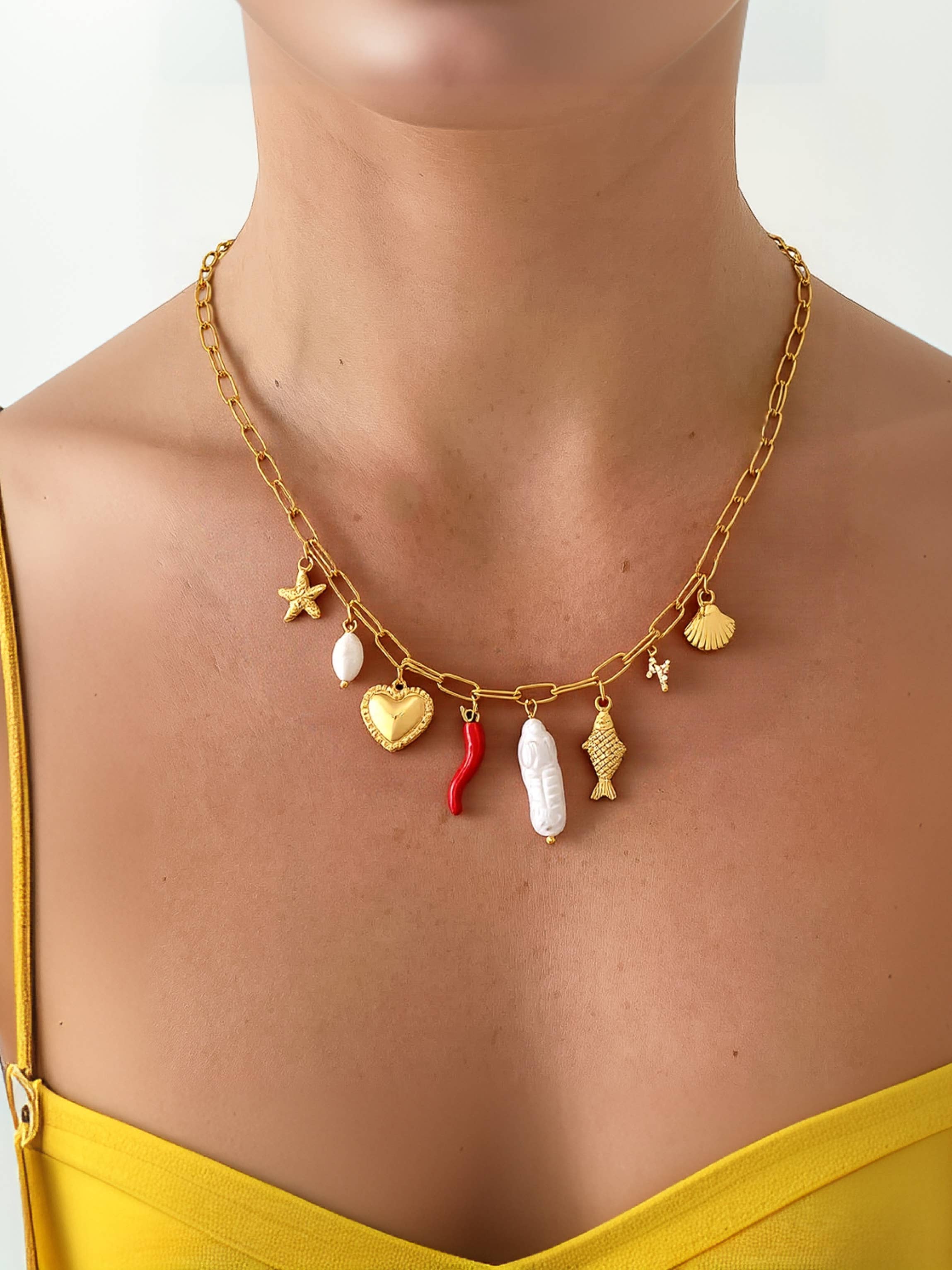 Delicate gold necklace featuring playful ocean-inspired charms—a fish and a pearl—on an 18K gold-plated stainless steel chain. Pendant measures 0.5 to 1.1 inches; chain is 17.7 inches with a 2-inch extender. Hypoallergenic, water- and tarnish-resistant—perfect worn solo or layered for a whimsical touch.