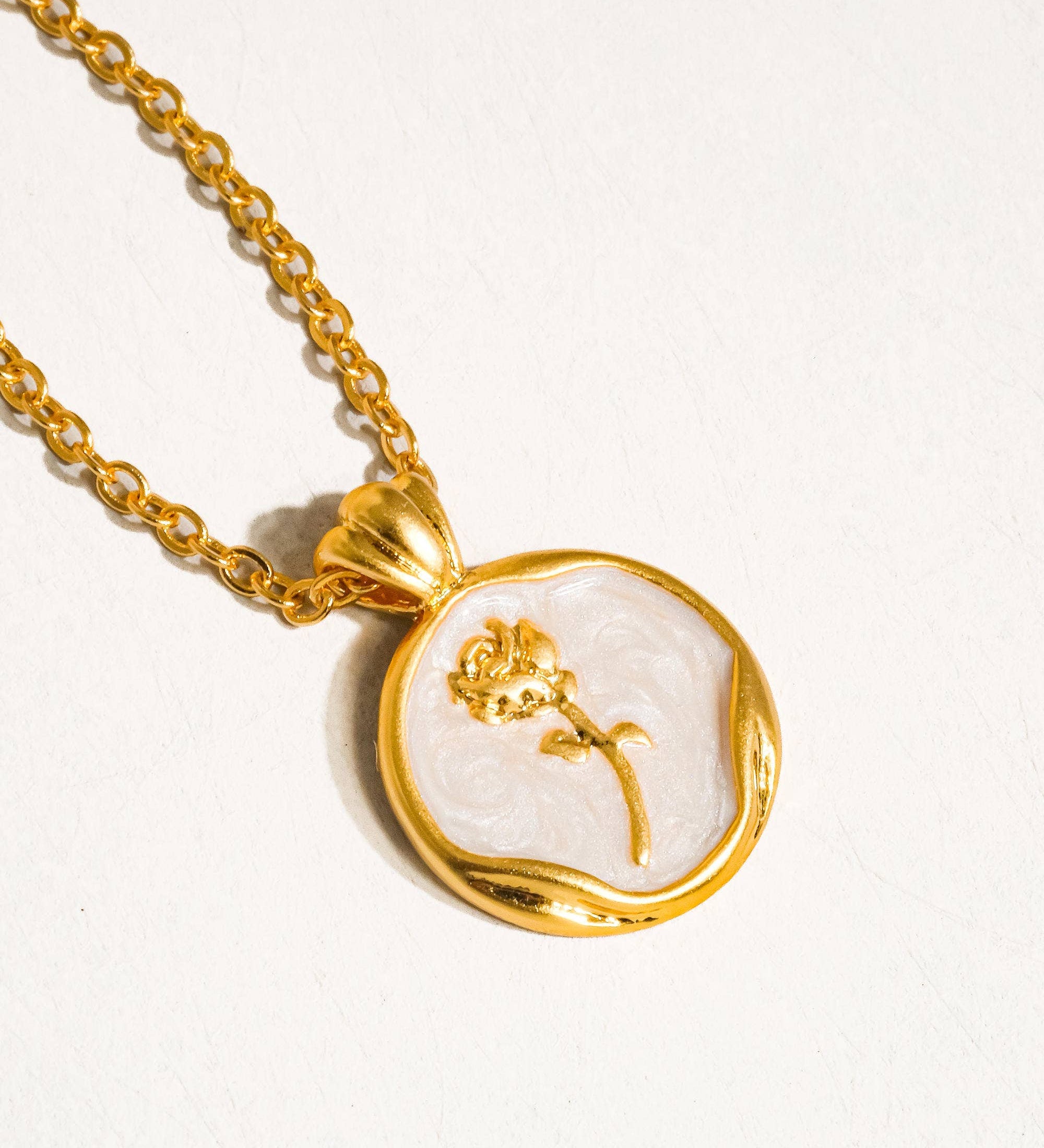 Delicate necklace crafted from 18K gold-plated brass, featuring a rose-engraved coin pendant (approx. 1.3cm diameter) on a fine chain measuring 40cm with a 5cm extender. Hypoallergenic, water- and tarnish-resistant—perfect for adding a timeless symbol of beauty and femininity to any look.