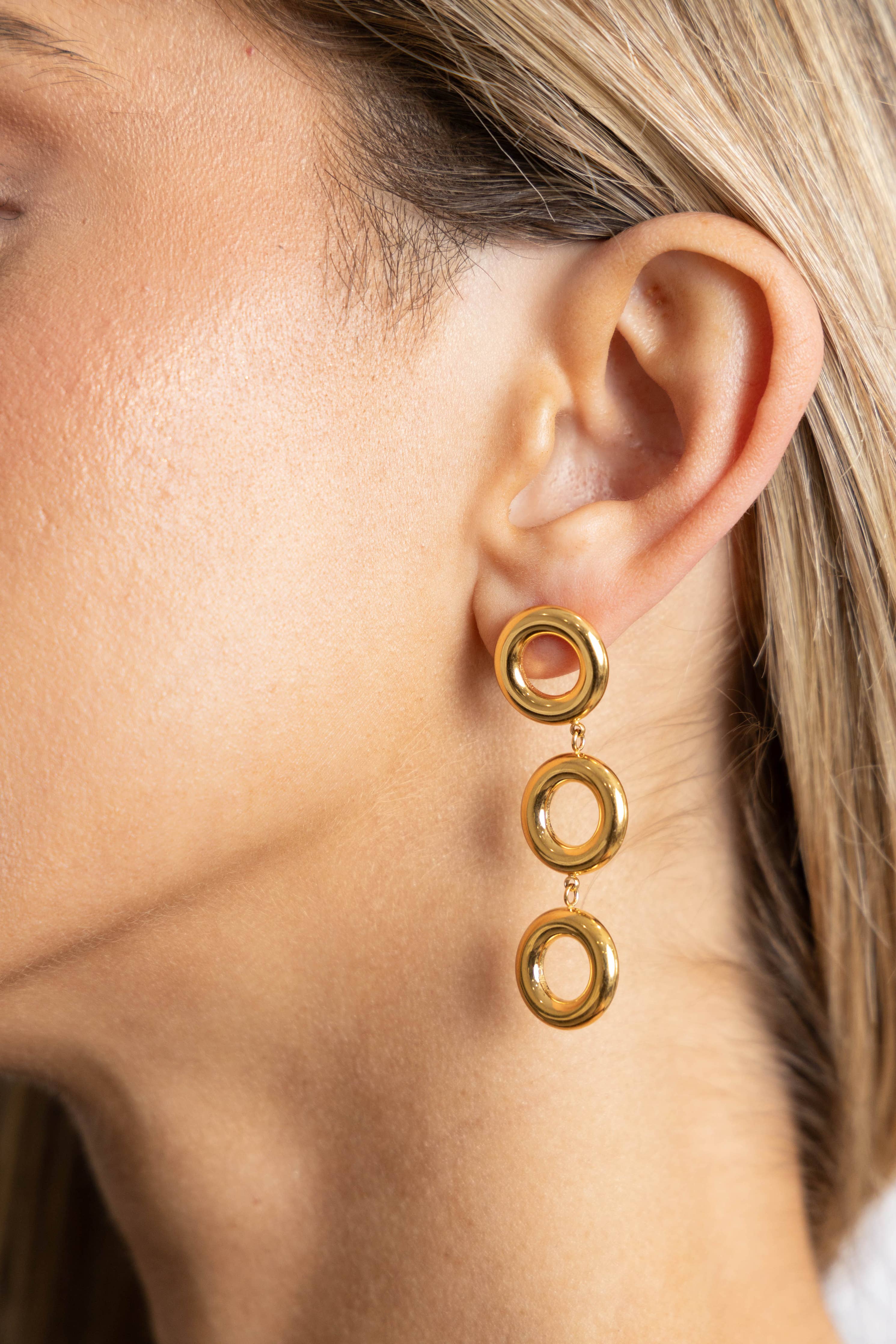 Close-up of a person wearing gold hoop earrings.