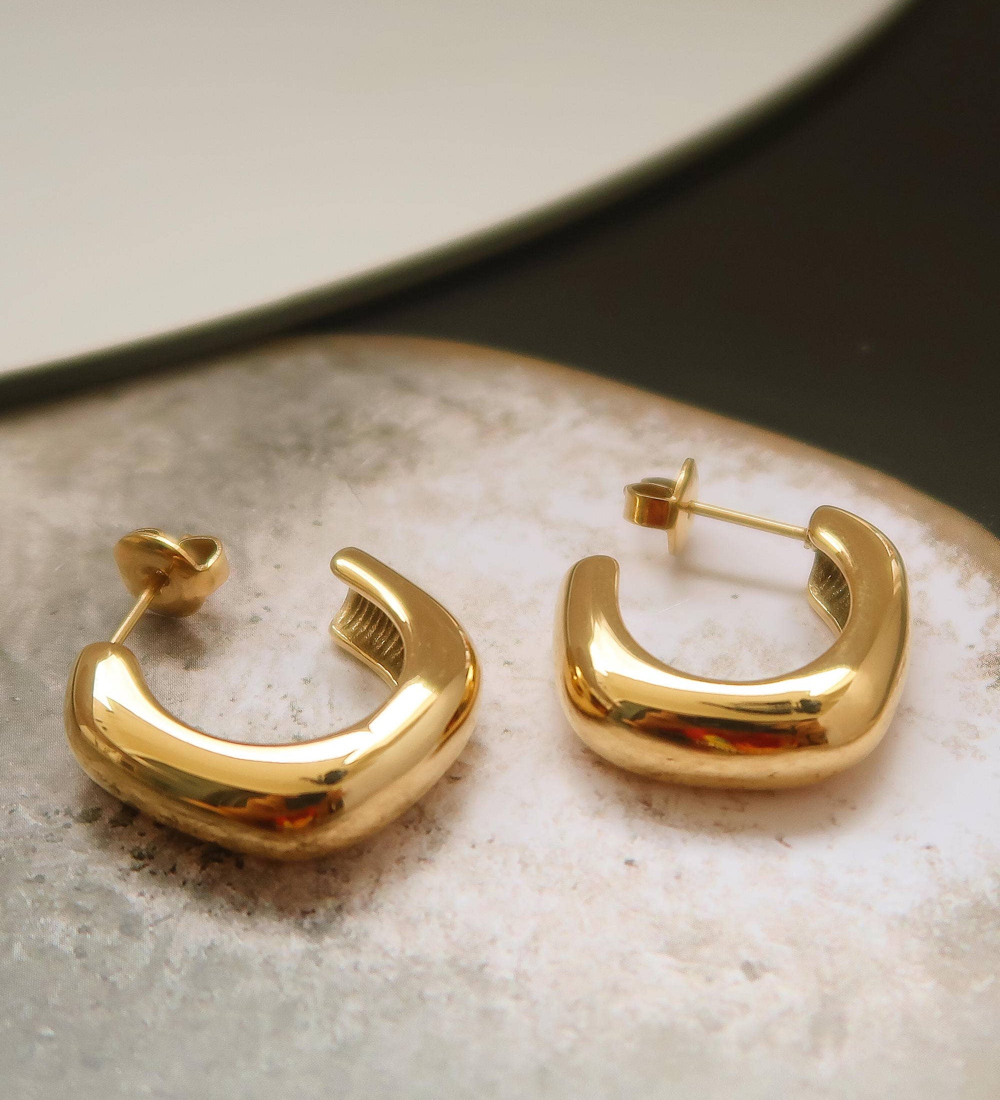 Gold hoop earrings on a textured surface