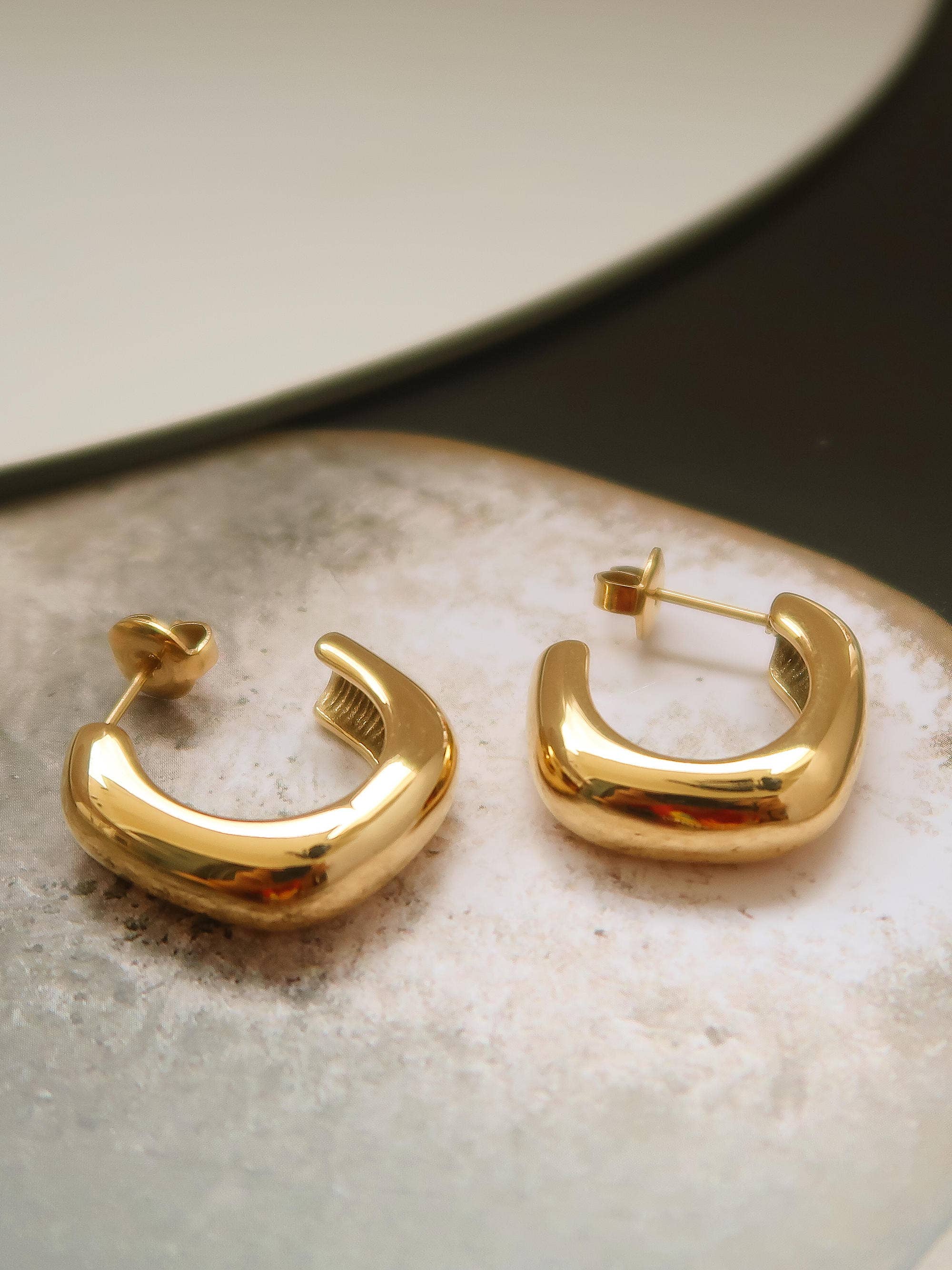 Gold hoop earrings on a textured surface