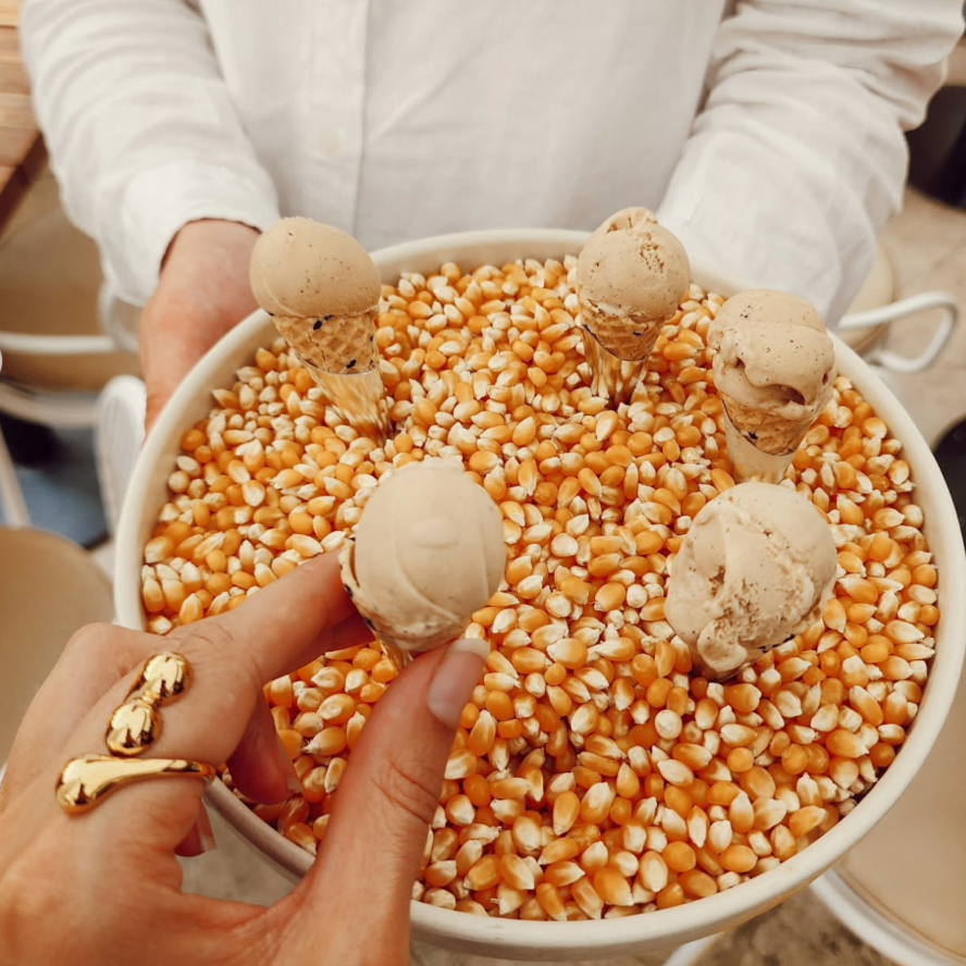 Person holding a bowl of popcorn with small round treats on top