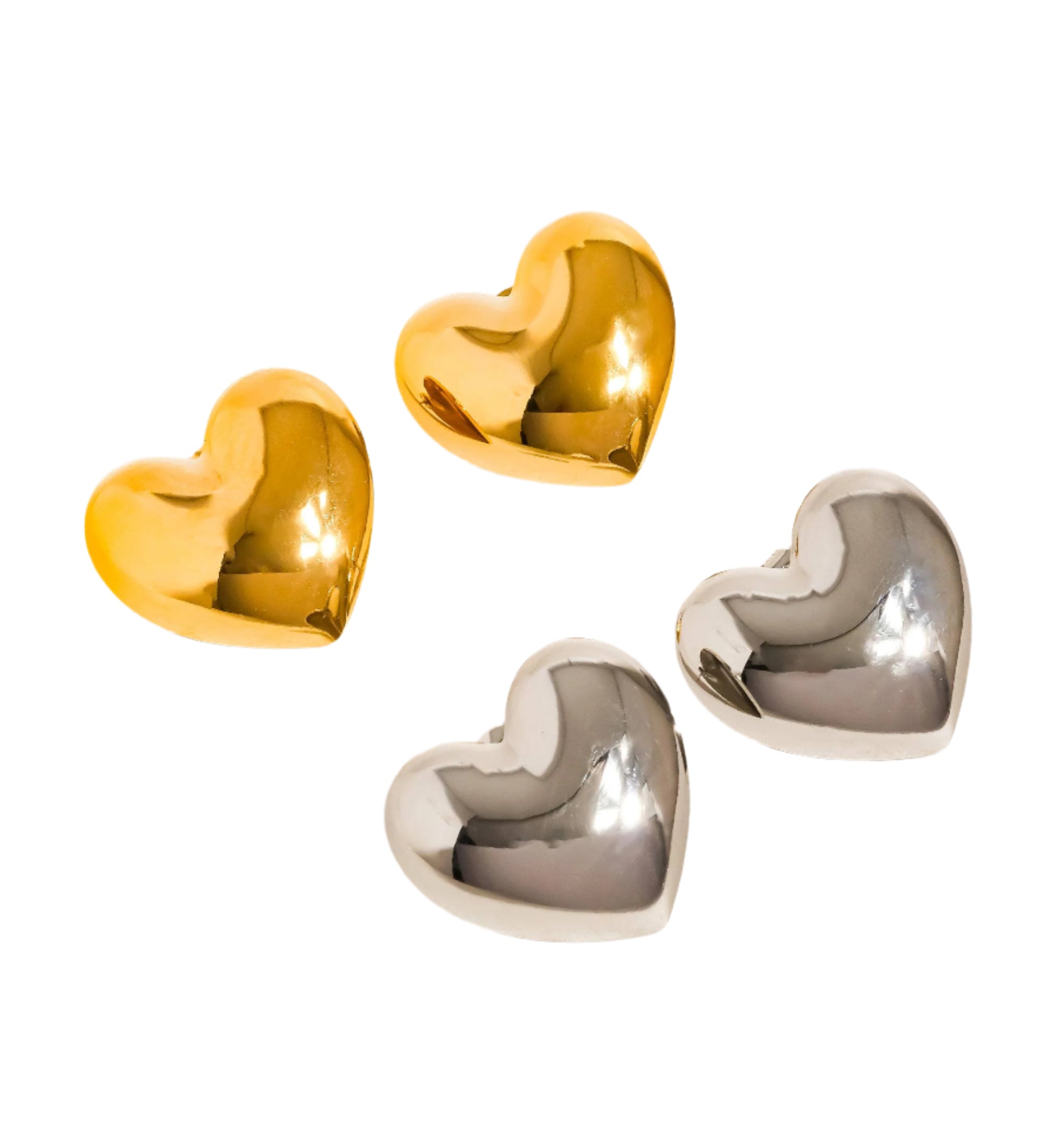 Gold heart-shaped stud earrings resting on a neutral-toned surface, with a soft light reflection.