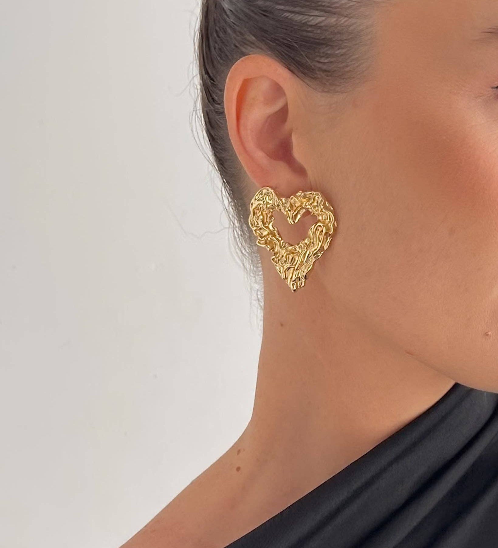 Sculpted heart stud earrings crafted from 18K gold PVD-plated stainless steel, featuring a unique textured design for added dimension and charm. Hypoallergenic, water- and tarnish-resistant—perfect for making a bold, romantic statement.