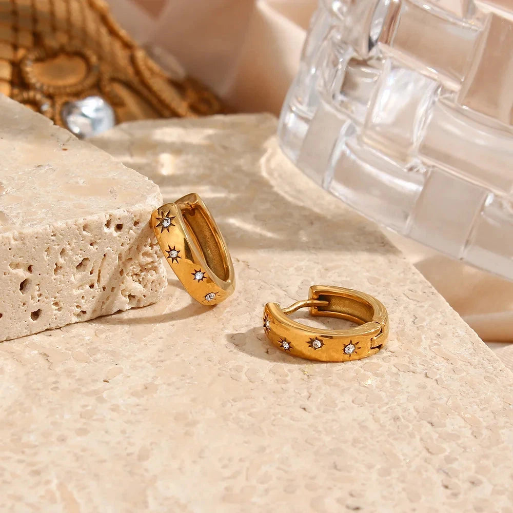Petite hoop earrings crafted from 18K gold-plated stainless steel, featuring delicate sunburst charms adorned with sparkling zircon detail symbolising light and energy. Hypoallergenic, water- and tarnish-resistant—perfect for adding modern elegance and radiant style to any look.