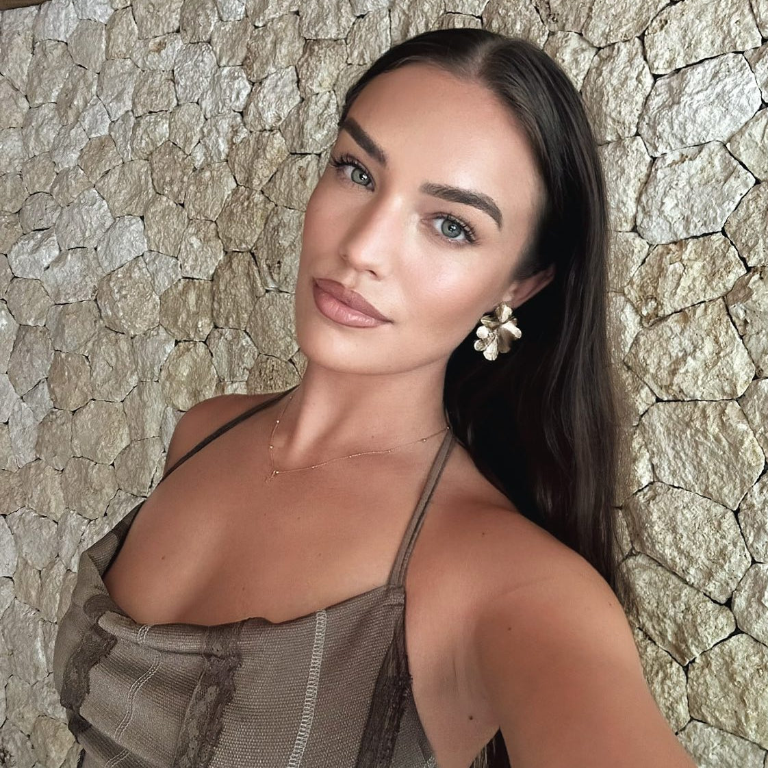 Woman taking a selfie against a stone wall