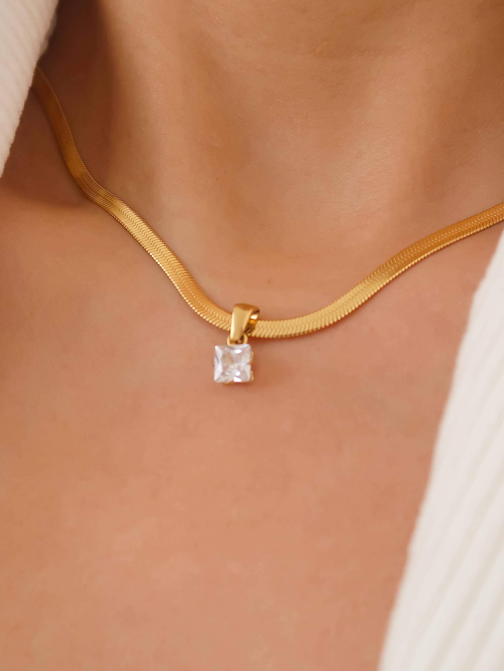 Sleek snake chain necklace crafted from premium stainless steel with 18K gold plating, featuring a square-cut cubic zirconia pendant (0.25” / 0.64cm) for refined sparkle. Hypoallergenic, water- and tarnish-resistant—perfect for effortless, modern elegance.