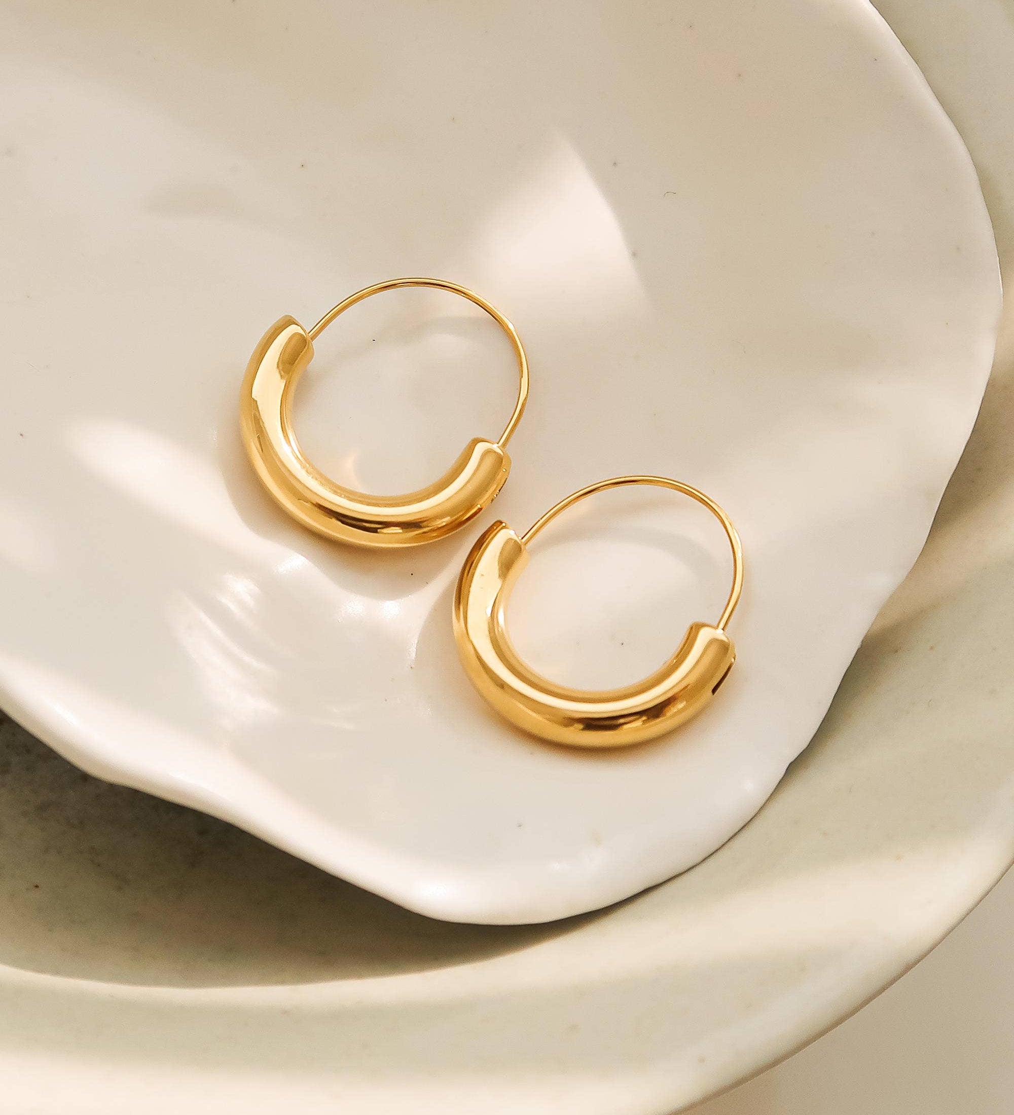Sleek U-shaped hoop earrings with a softly polished finish, crafted for a modern twist on a timeless silhouette. Made from hypoallergenic, water- and tarnish-resistant materials—perfect for adding effortless sophistication to both casual and dressy looks.