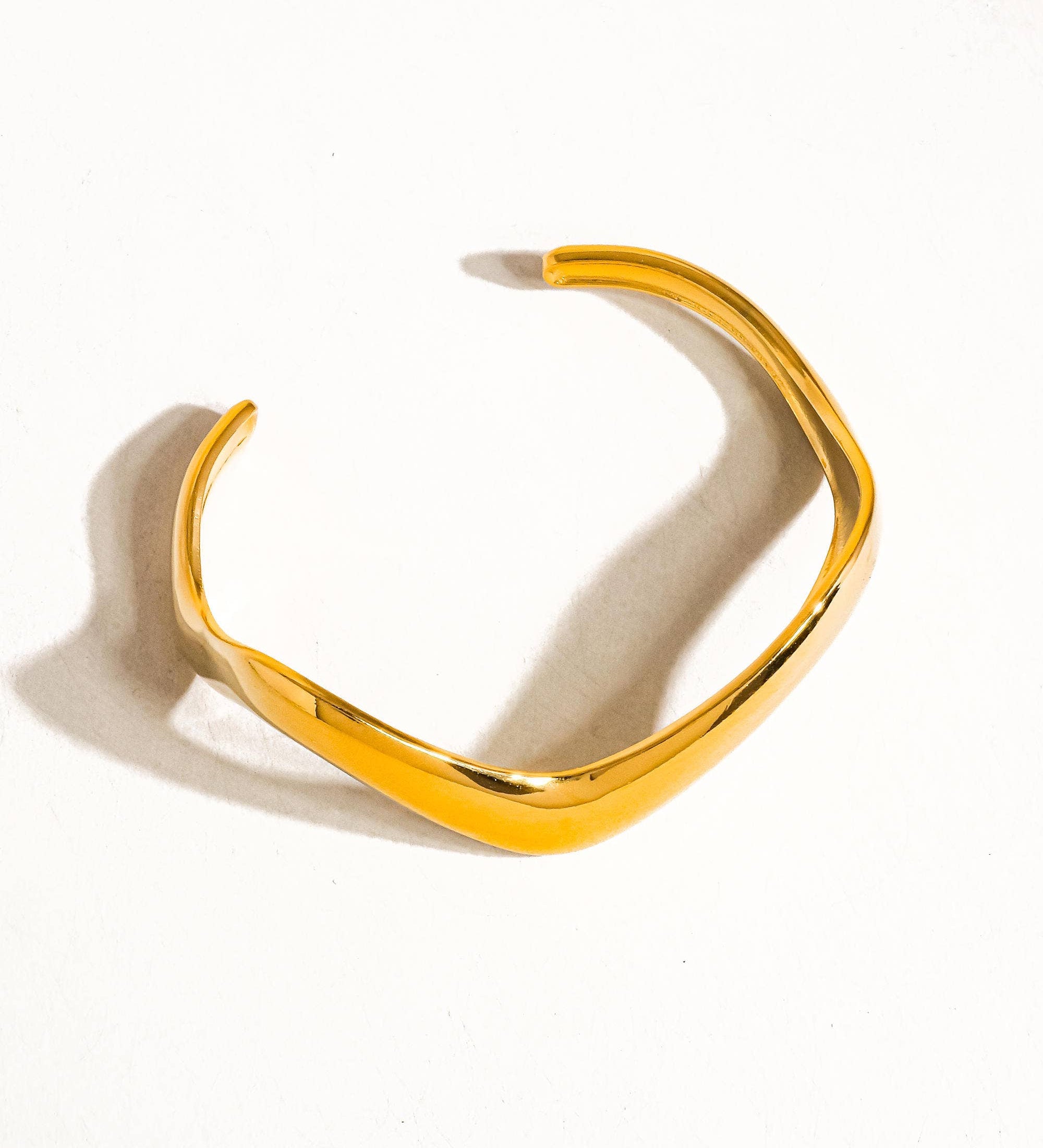 Sleek V-shaped bangle bracelet crafted from 18K gold-plated stainless steel, featuring a minimalist design with contemporary edge. Hypoallergenic, water- and tarnish-resistant—perfect for versatile styling, layering, or wearing solo for effortless sophistication.