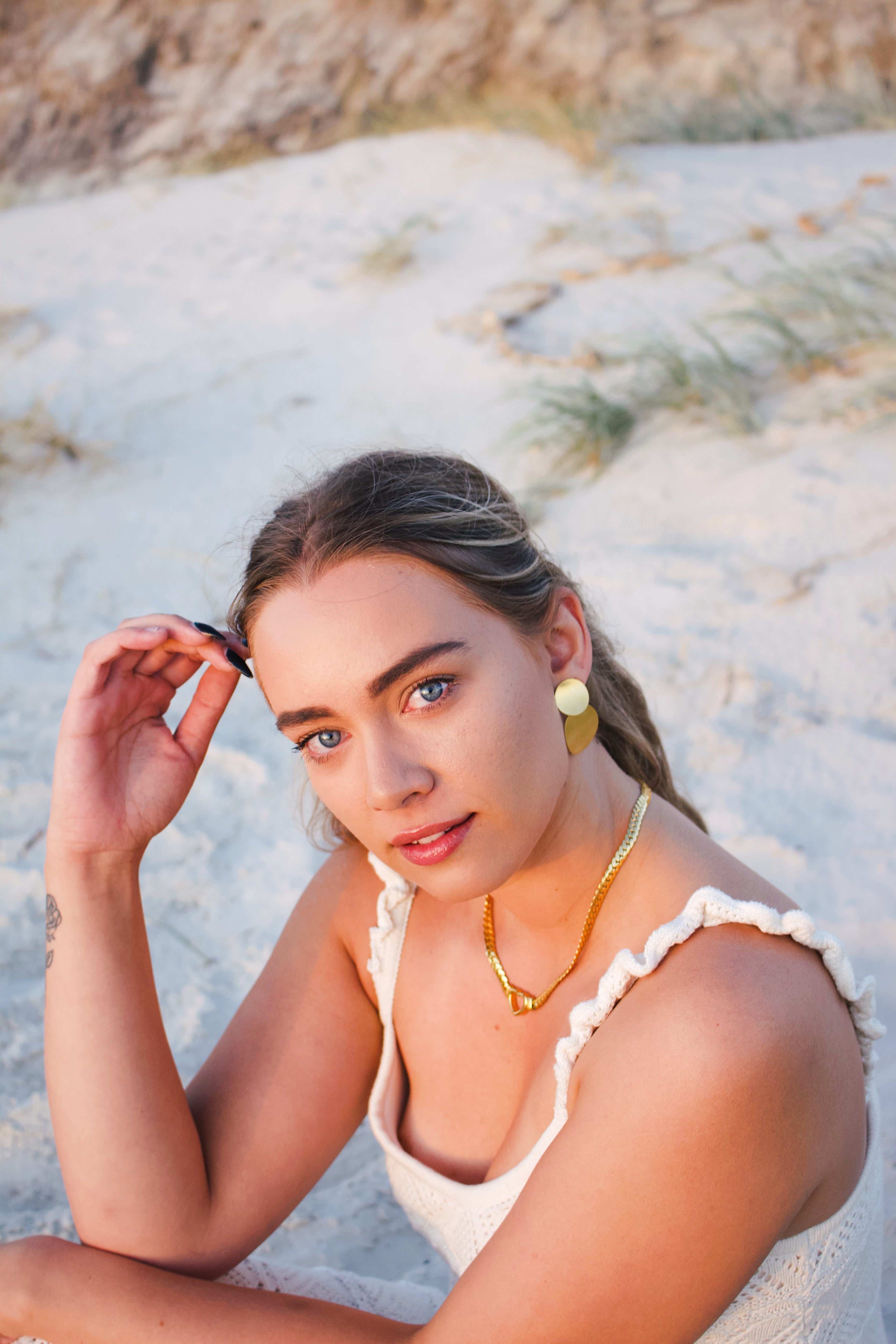 Woman sitting on a sandy beach with a blurred natural background
