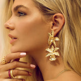 Statement earrings crafted from stainless steel with premium 18K gold plating, featuring a bold sculpted flower motif. Hypoallergenic, nickel-free, water- and tarnish-resistant—perfect for adding floral elegance and standout charm to any outfit.