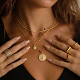 Close-up of a person wearing gold necklaces and rings with a blurred background