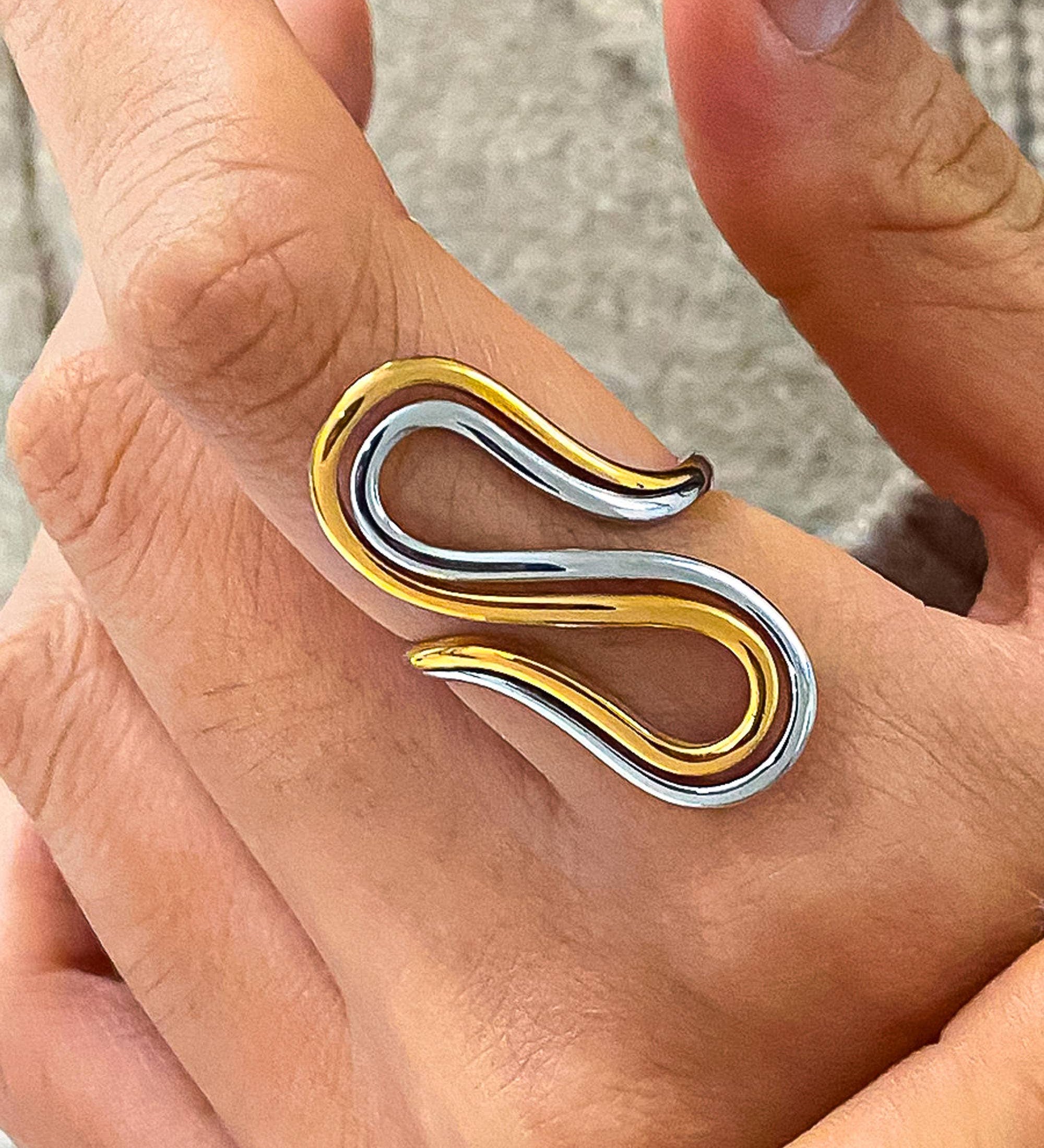 Artistic two-tone ring with a sculptural silhouette, fluid curves, and modern asymmetry. Crafted from 18K gold-plated stainless steel in US size 7 (0.682" diameter). Hypoallergenic, water- and tarnish-resistant—ideal as a bold solo piece or stacked for contrast.