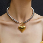 Close-up of the Ayla Necklace featuring a two-tone gold and silver heart pendant on a gold chain, displayed against a neutral background.