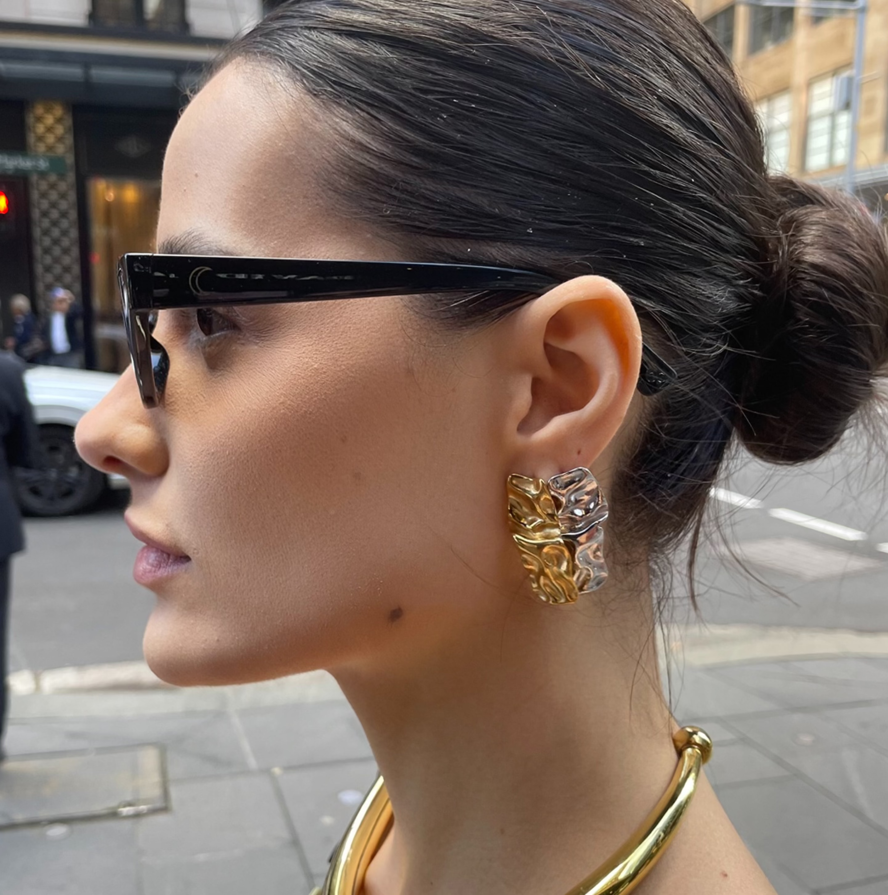 Woman in city street wearing gold necklace and earrings